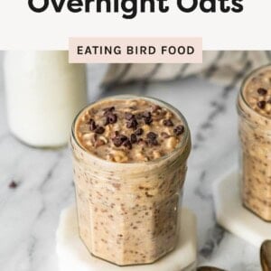 Jar of cookie dough overnight oats topped with mini chocolate chips on a marble counter.