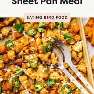 Sheet pan of hot honey chicken with roasted sweet potatoes, jalapeño slices, feta, and fresh herbs.