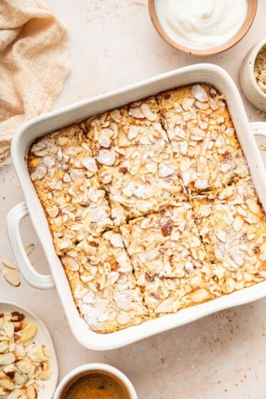 Square pan of baked oatmeal topped with sliced almonds and sugar.