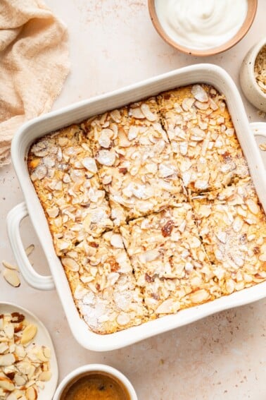 Square pan of baked oatmeal topped with sliced almonds and sugar.