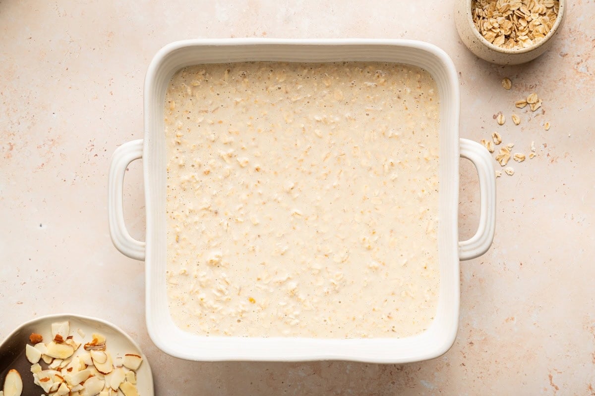 Baked oatmeal batter spread evenly in square ceramic baking dish.