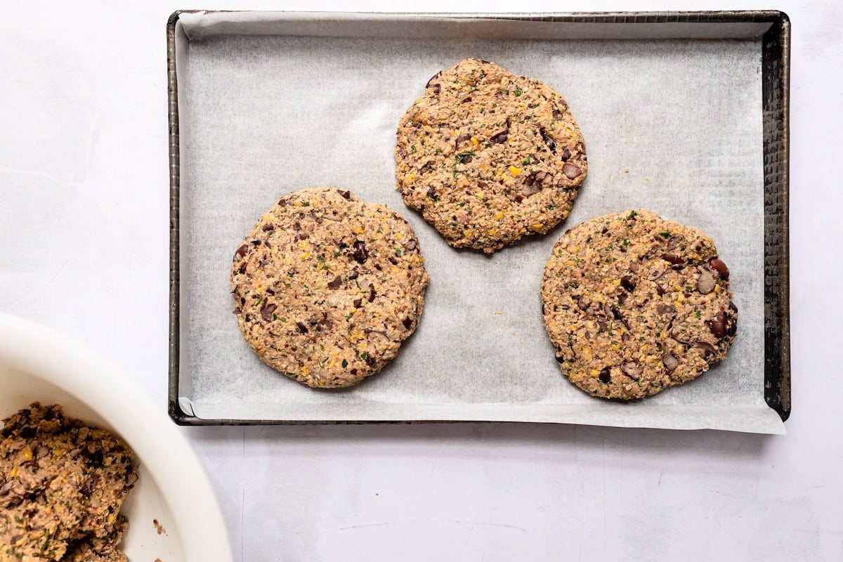 Black bean burger patties on a metal tray with parchment paper.