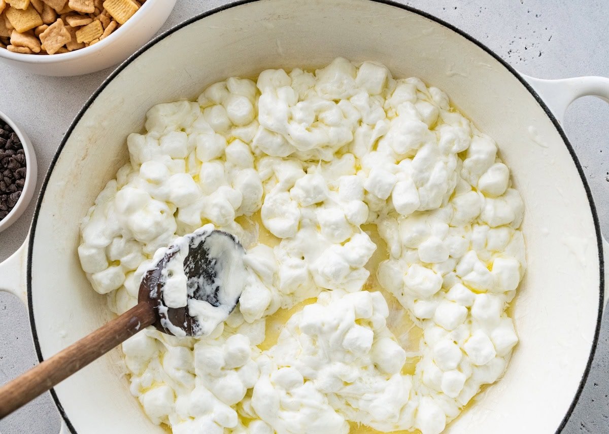 A large white pot with melted mini marshmallows and a wooden spoon.