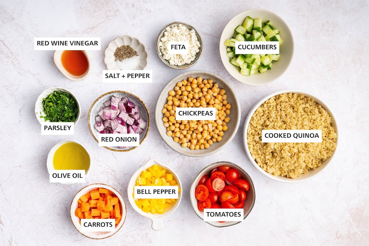 Quinoa Chickpea Salad ingredients: Cooked quinoa, cucumbers, chickpeas, tomatoes, feta, bell pepper, red onion, carrots, red wine vinegar, olive oil, parsley, pepper, salt.
