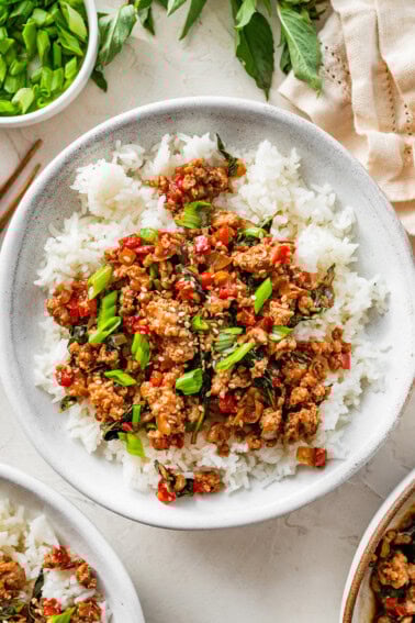 Thai basil chicken served over fluffy jasmine rice with fresh basil and green onions on top.