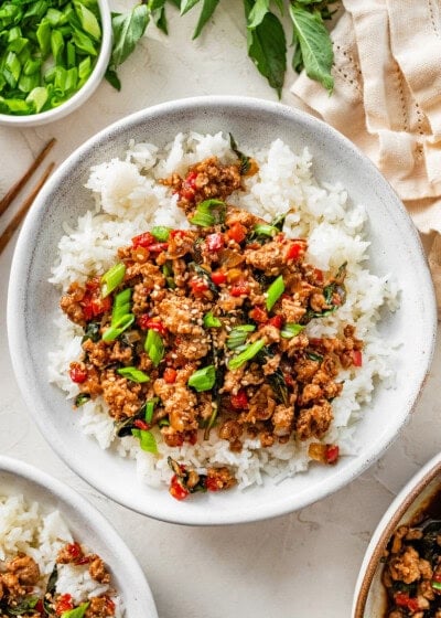 Thai basil chicken served over fluffy jasmine rice with fresh basil and green onions on top.
