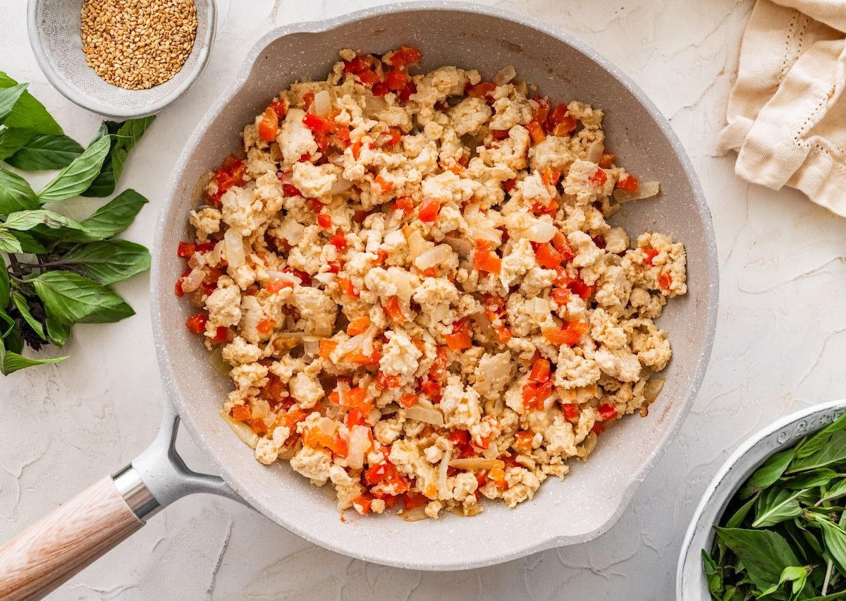 Ground chicken and diced bell pepper mixture cooking in a skillet before adding sauce.
