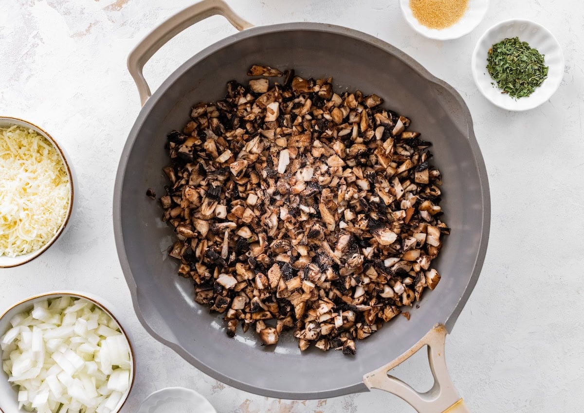 Sautéed mushrooms in skillet for cottage cheese egg bake with browned edges.