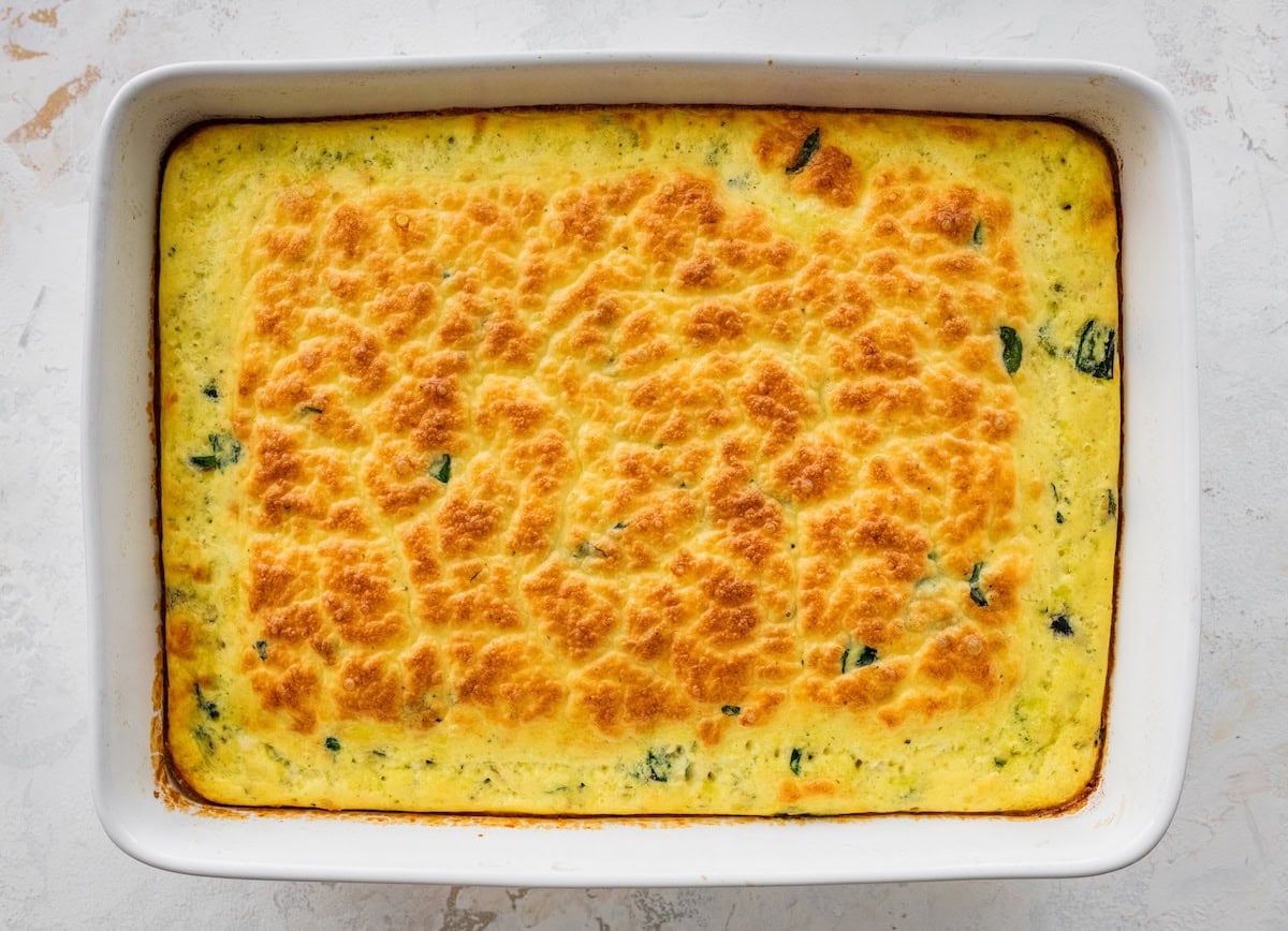 Baked cottage cheese egg casserole in dish with golden, cheesy top and spinach throughout.