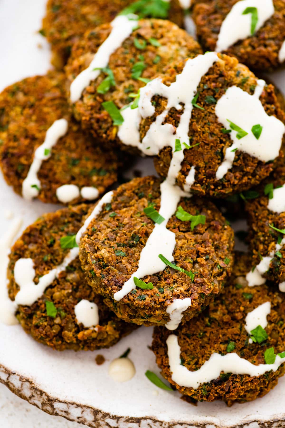 Baked falafel patties drizzled with tahini sauce and sprinkled with fresh herbs.