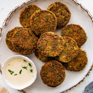 Plate of crispy baked falafel patties served with creamy dipping sauce.