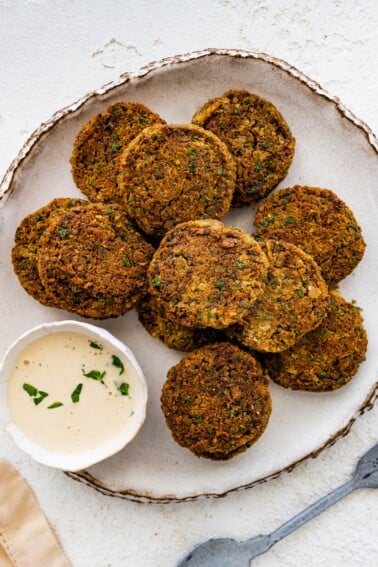 Plate of crispy baked falafel patties served with creamy dipping sauce.