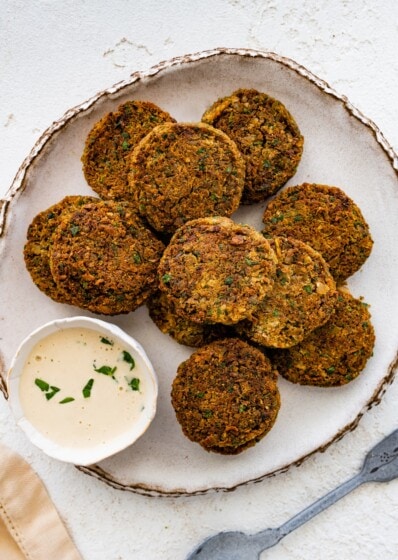 Plate of crispy baked falafel patties served with creamy dipping sauce.