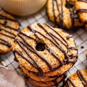 Multiple banana samoas cookies stacked on each other on a cooling rack.