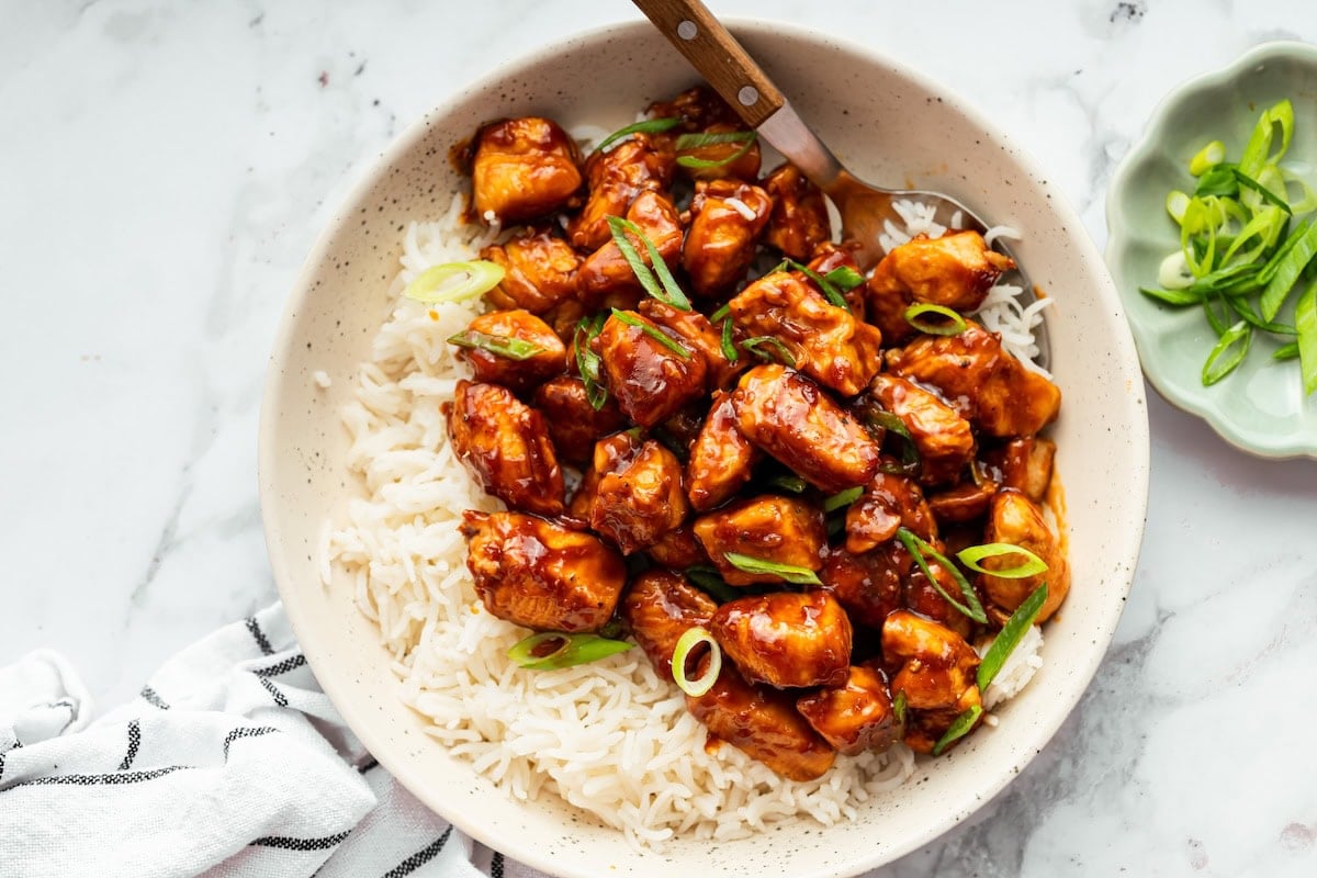 Sweet and savory bourbon chicken served over fluffy rice in a bowl.