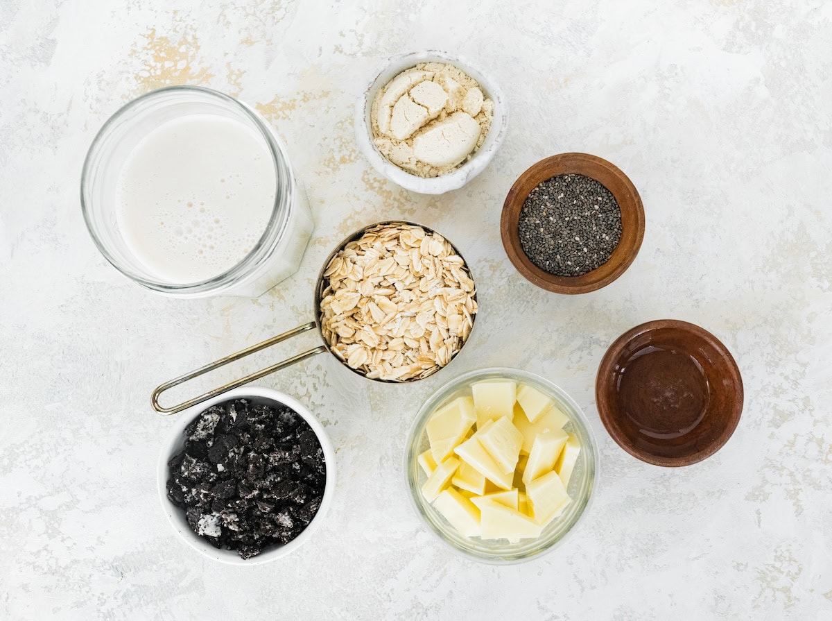Ingredients measured out to make Cookies and Cream Overnight Oats: sandwich cookies, almond milk, protein powder, oats, white chocolate, chia seeds and coconut oil.