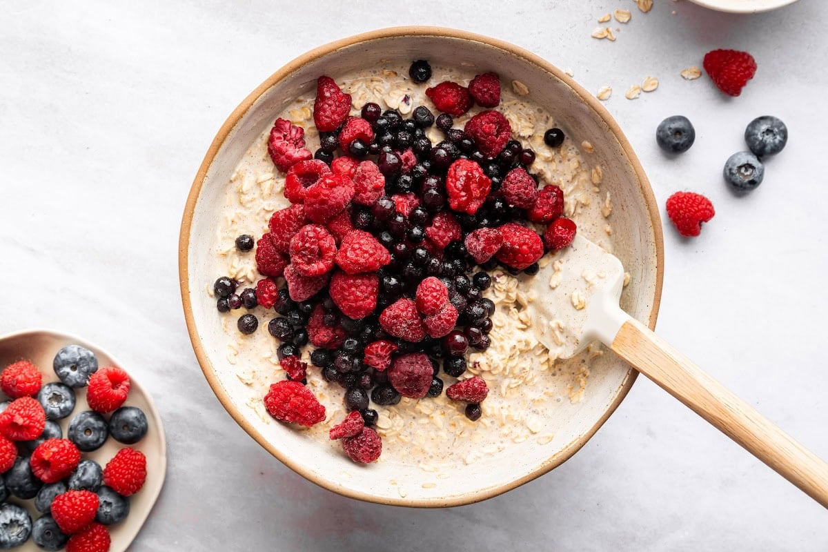 Mixed berries added to a mixing bowl with the baked oatmeal cup mixture.