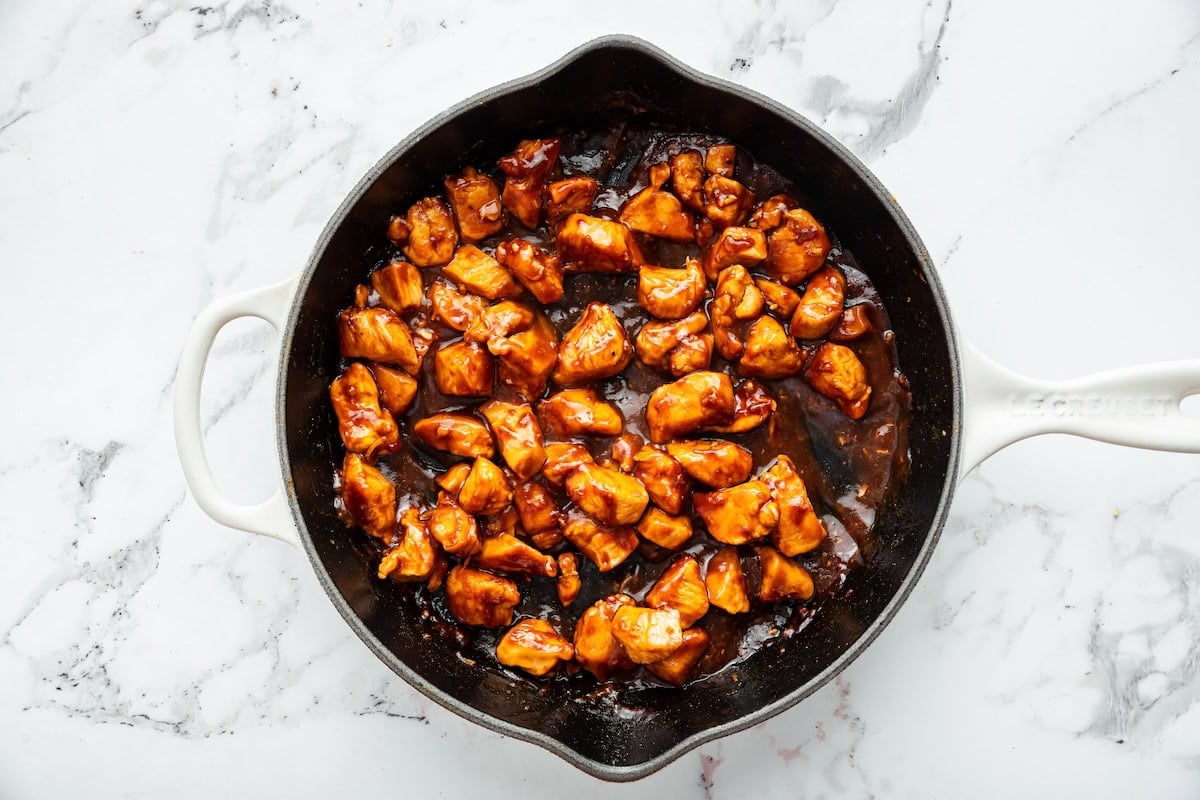 Diced chicken cooking in a skillet, starting to brown for an easy homemade glazed chicken.