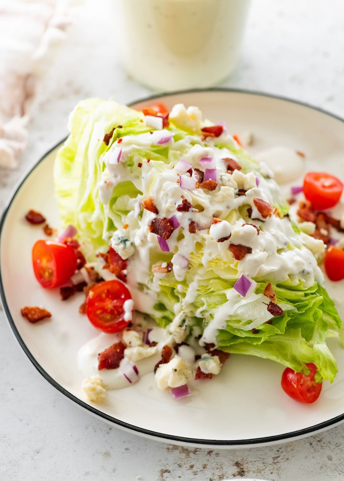 A salad with romaine lettuce, cherry tomatoes, red onion, and a drizzle of greek yogurt blue cheese dressing.