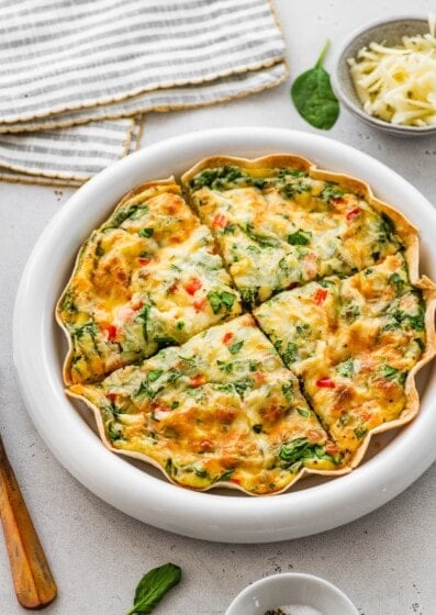 Single-serve tortilla quiche sliced into wedges showing spinach, peppers, and cheesy egg filling.