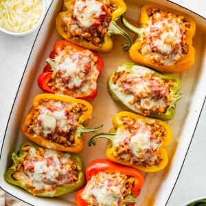 A pan of 8 cooked pepper halves stuffed with ground turkey and topped with melted cheese.