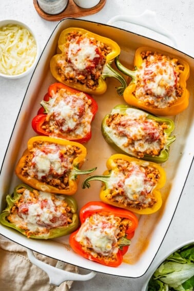 A pan of 8 cooked pepper halves stuffed with ground turkey and topped with melted cheese.