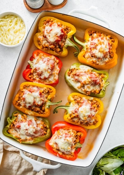 A pan of 8 cooked pepper halves stuffed with ground turkey and topped with melted cheese.
