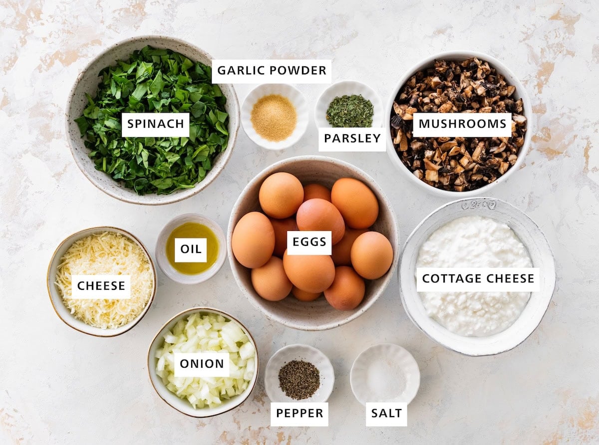 Ingredients for baked cottage cheese eggs: spinach, eggs, cottage cheese, mushrooms, cheese, onion, salt, pepper, oil, parsley and garlic powder.