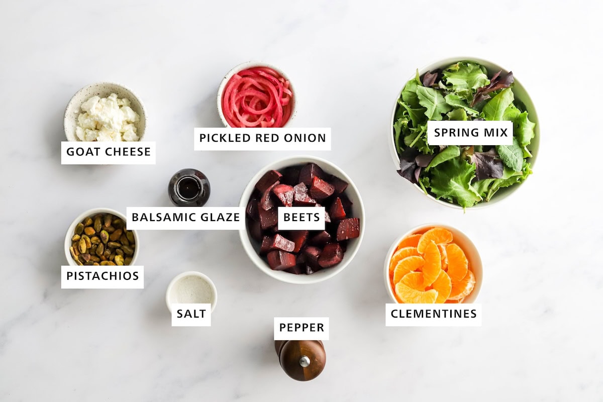 Ingredients measured out to make a baby beet and clementine salad: spring mix, clementines, beets, pickled red onions, pepper, salt, balsamic glaze/dressing, goat cheese and pistachios.