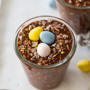 2 Cadbury mini egg overnight oats in glass jars each topped with 3 Cadbury eggs.