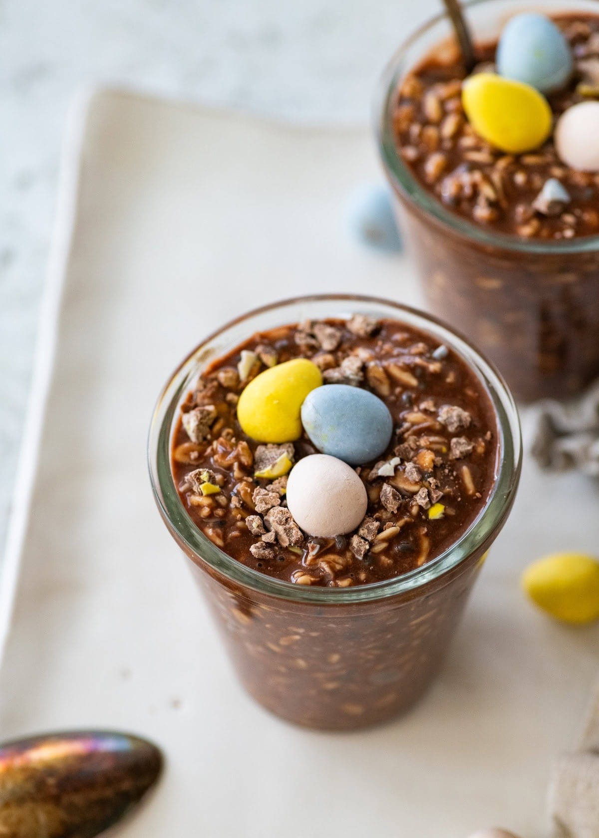 A glass jar with chocolate overnight oats with cadbury mini eggs.