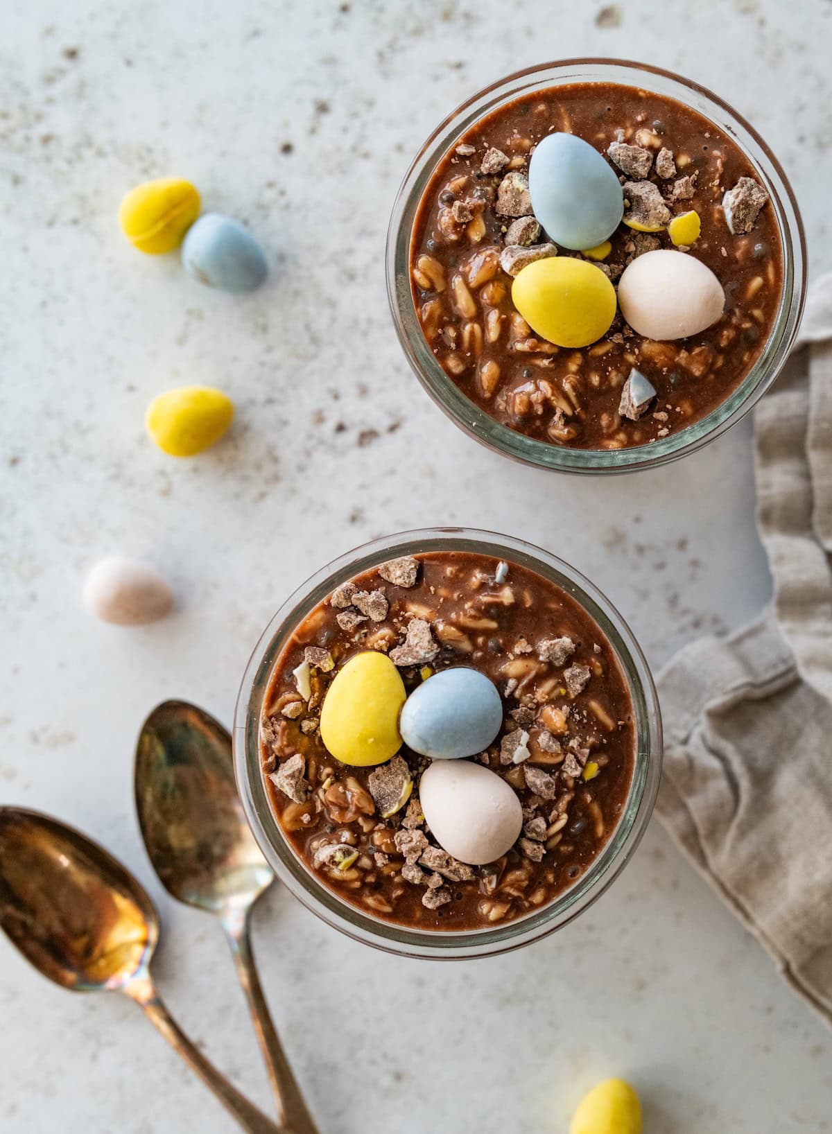 Two glass jars of cadbury mini egg overnight oats topped with three mini cadbury eggs.