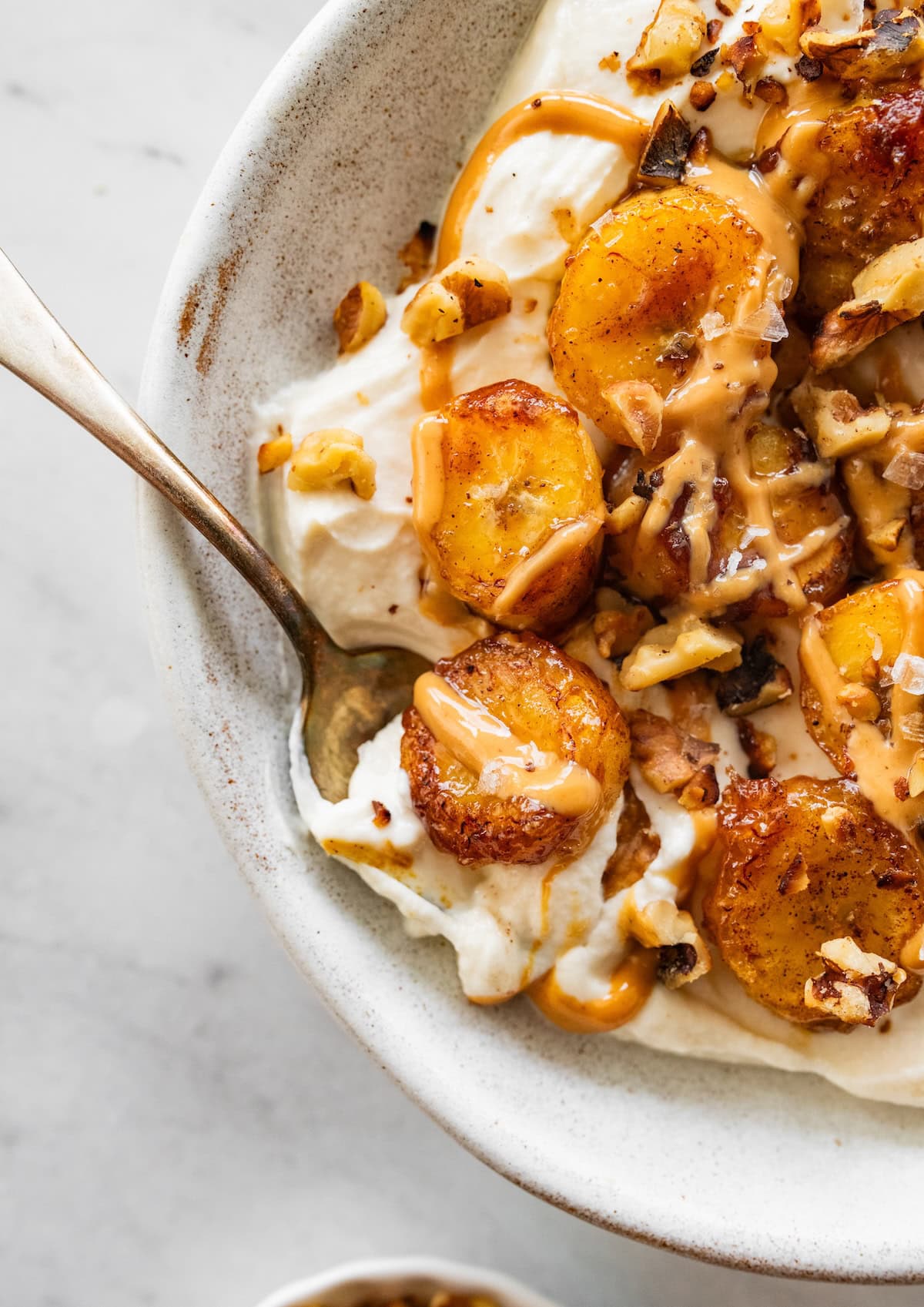 A spoonful of a caramelized banana yogurt bowl with a peanut butter drizzle.