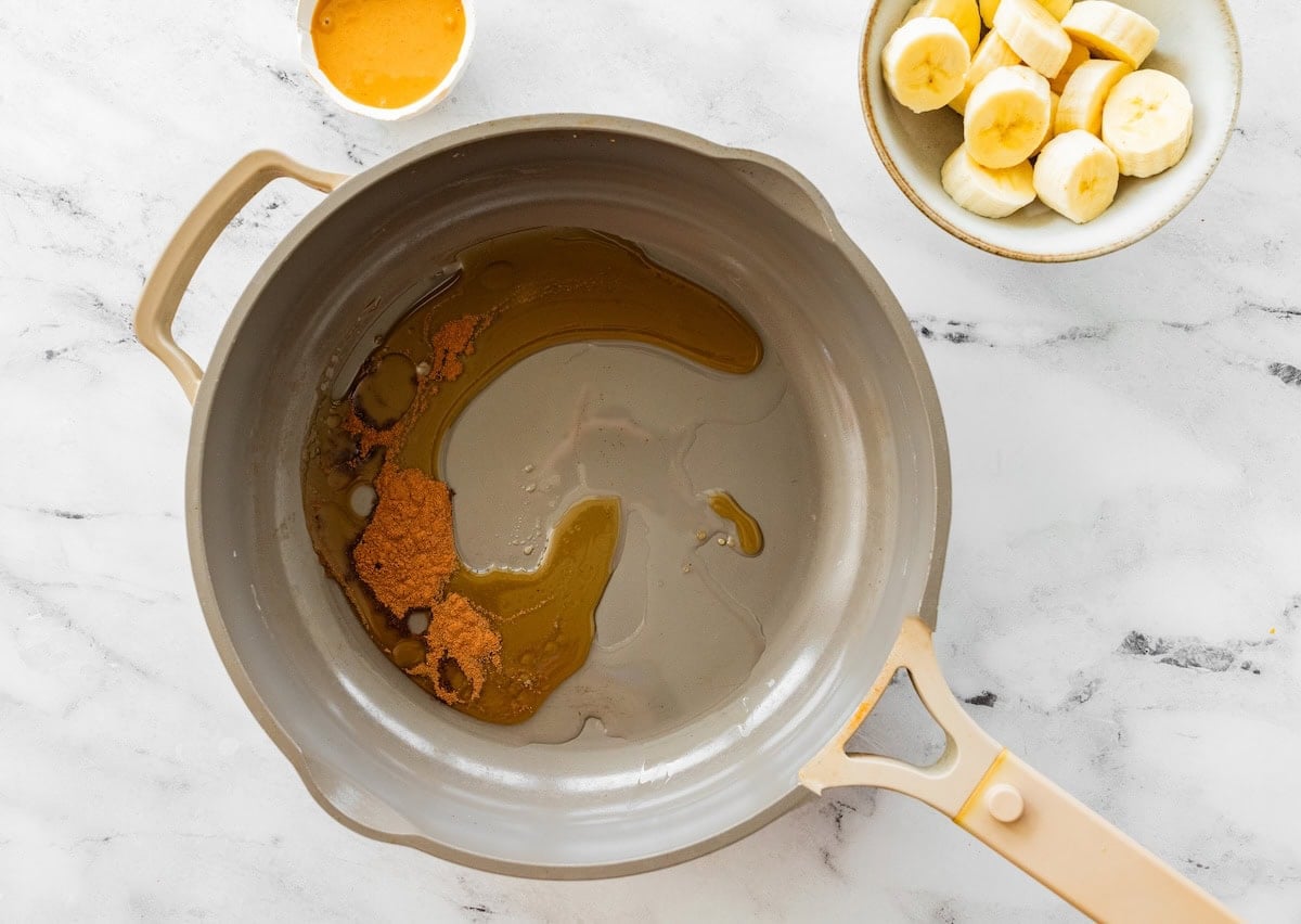 Cinnamon, and maple syrup being heated up in a pan.