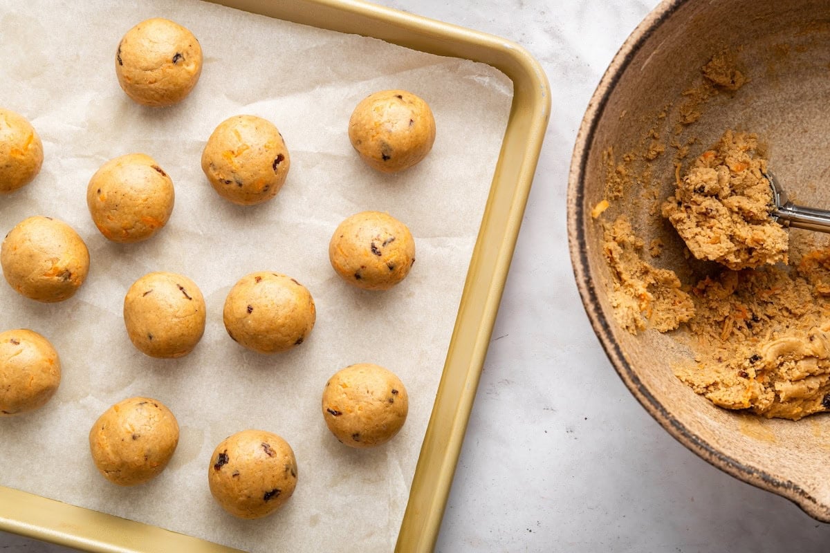 Uncoated carrot cake protein balls rolled and placed on parchment-lined baking sheet.