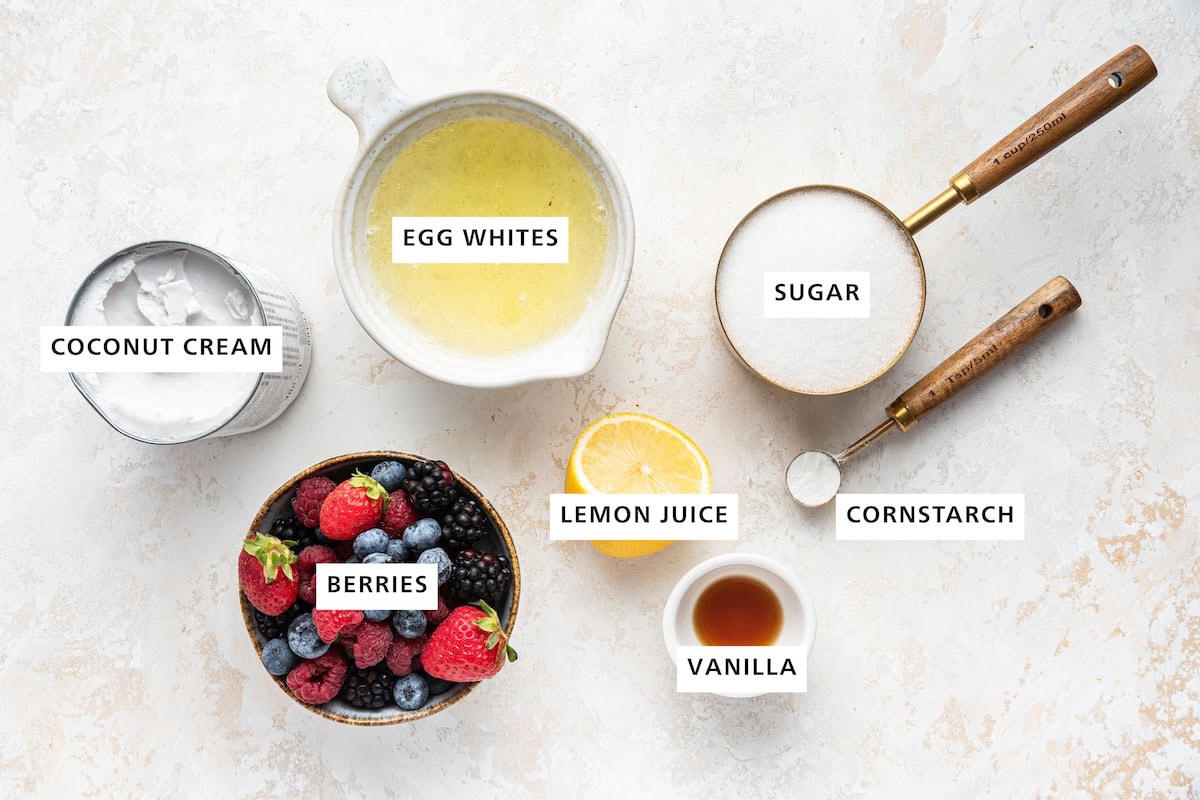 Ingredients measured out to make a Pavlova: coconut cream, berries, egg whites, lemon juice, vanilla, sugar and cornstarch/arrowroot.