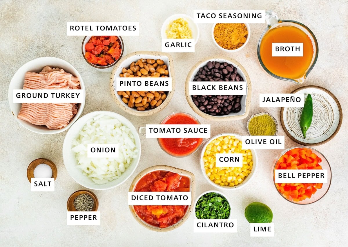 Ingredients measured out to make taco soup: ground turkey, salt pepper, onion, rotel tomatoes, pinto beans, diced tomatoes, tomato sauce, garlic, black beans, cilantro, corn, olive oil, taco seasoning, lime, bell pepper, jalapeño and broth.