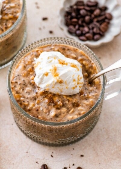 Brown sugar espresso overnight oats topped with whipped cream and brown sugar in glass bowl.