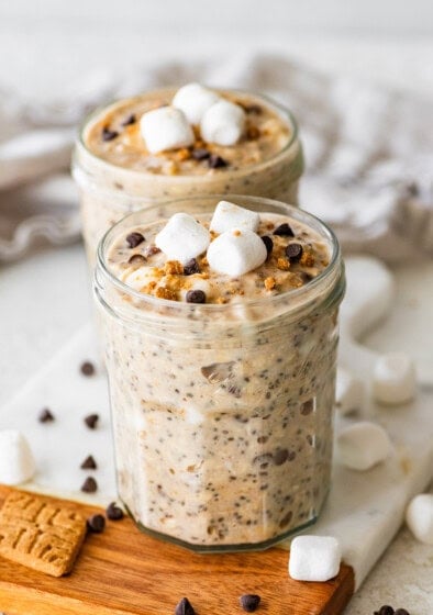 Two glass jars of s'mores overnight oats with marshmallows and chocolate chips.