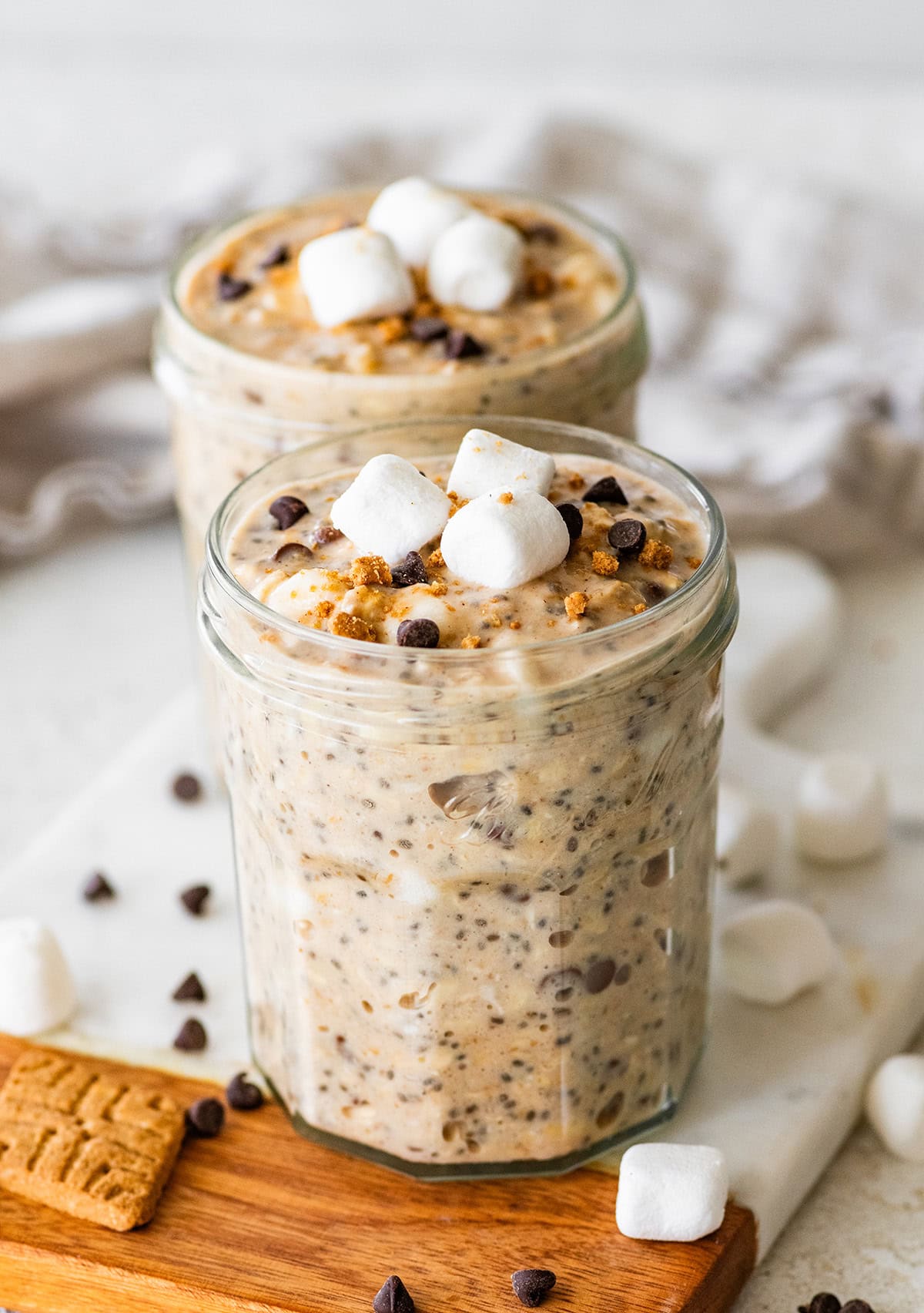 Two glass jars of s'mores overnight oats with marshmallows and chocolate chips.
