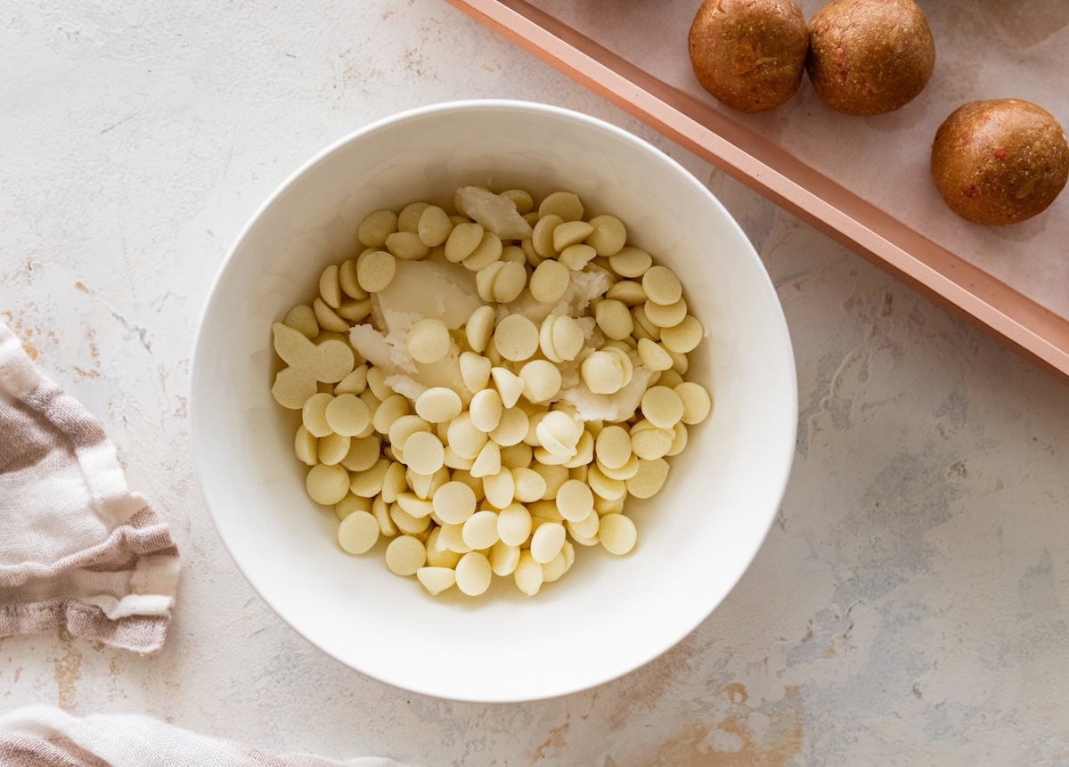 White chocolate chips in a bowl for strawberry protein ball coating.