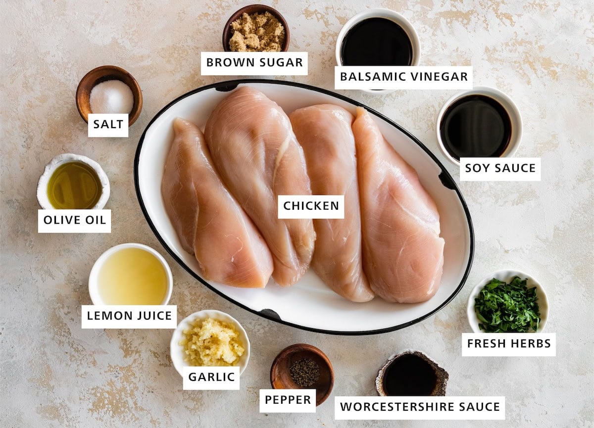 Ingredients measured out to make Chicken Marinade: soy sauce, fresh herbs, balsamic vinegar, worcestershire sauce, chicken brown sugar, pepper, garlic, salt, olive oil and lemon juice.