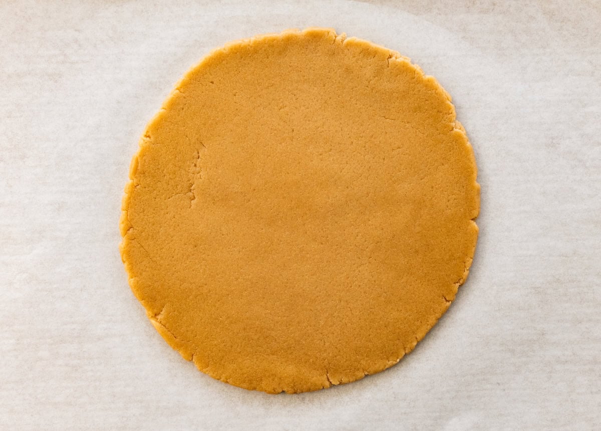 Rolled-out sugar cookie dough pressed into a flat circle for fruit pizza crust.