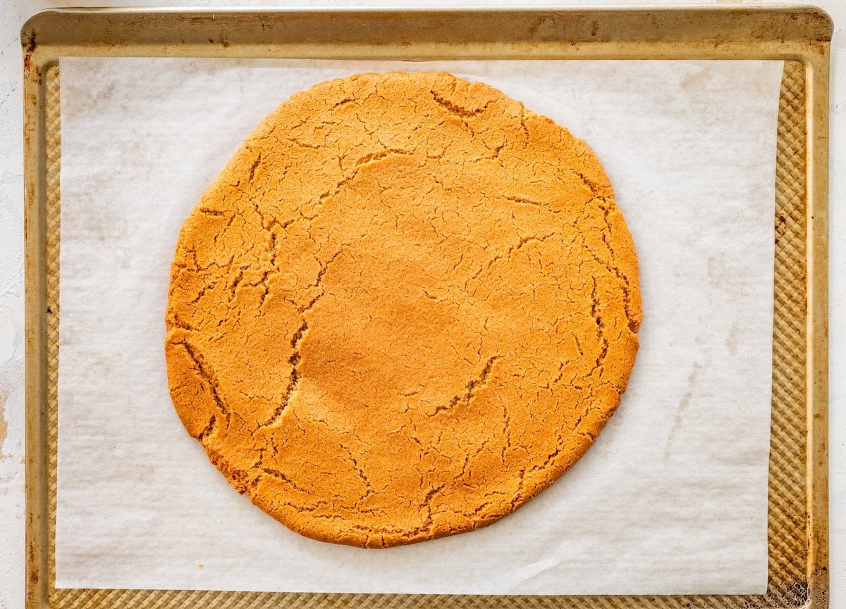 Baked sugar cookie crust on a parchment-lined baking sheet, lightly golden.