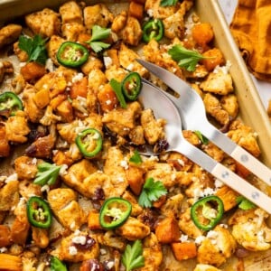 Hot honey glazed chicken on a baking sheet with roasted cauliflower, sweet potatoes, jalape&ntilde;o slices, feta, and cilantro.