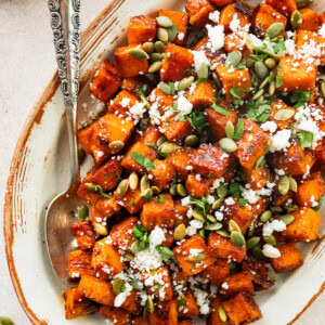Rroasted Mexican sweet potatoes served on a platter garnished with cotija cheese, pepitas, cilantro and hot honey.