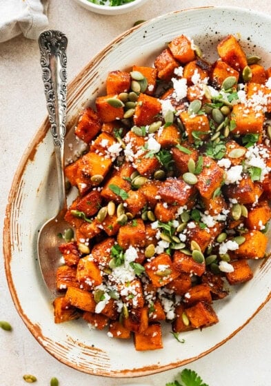 Rroasted Mexican sweet potatoes served on a platter garnished with cotija cheese, pepitas, cilantro and hot honey.