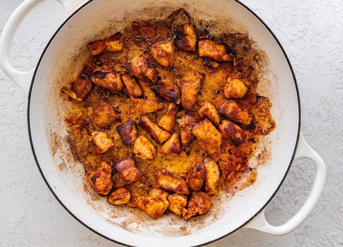 Seasoned chicken cooking in a large pot.