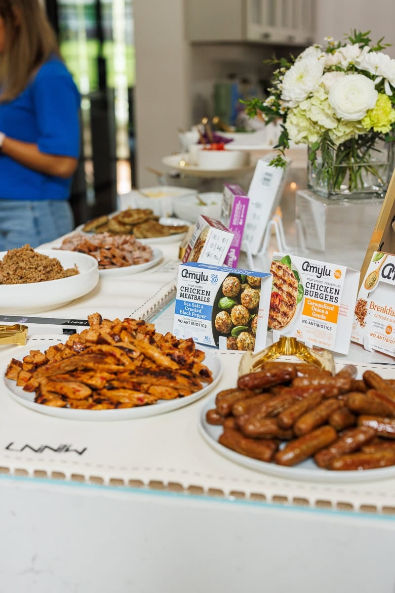 Amylu Foods product tasting table with chicken sausages, chicken meatballs, and prepared sides.