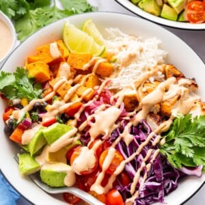 A serving of a BBQ chicken bowl with fresh vegetables and ranch dressing drizzle.